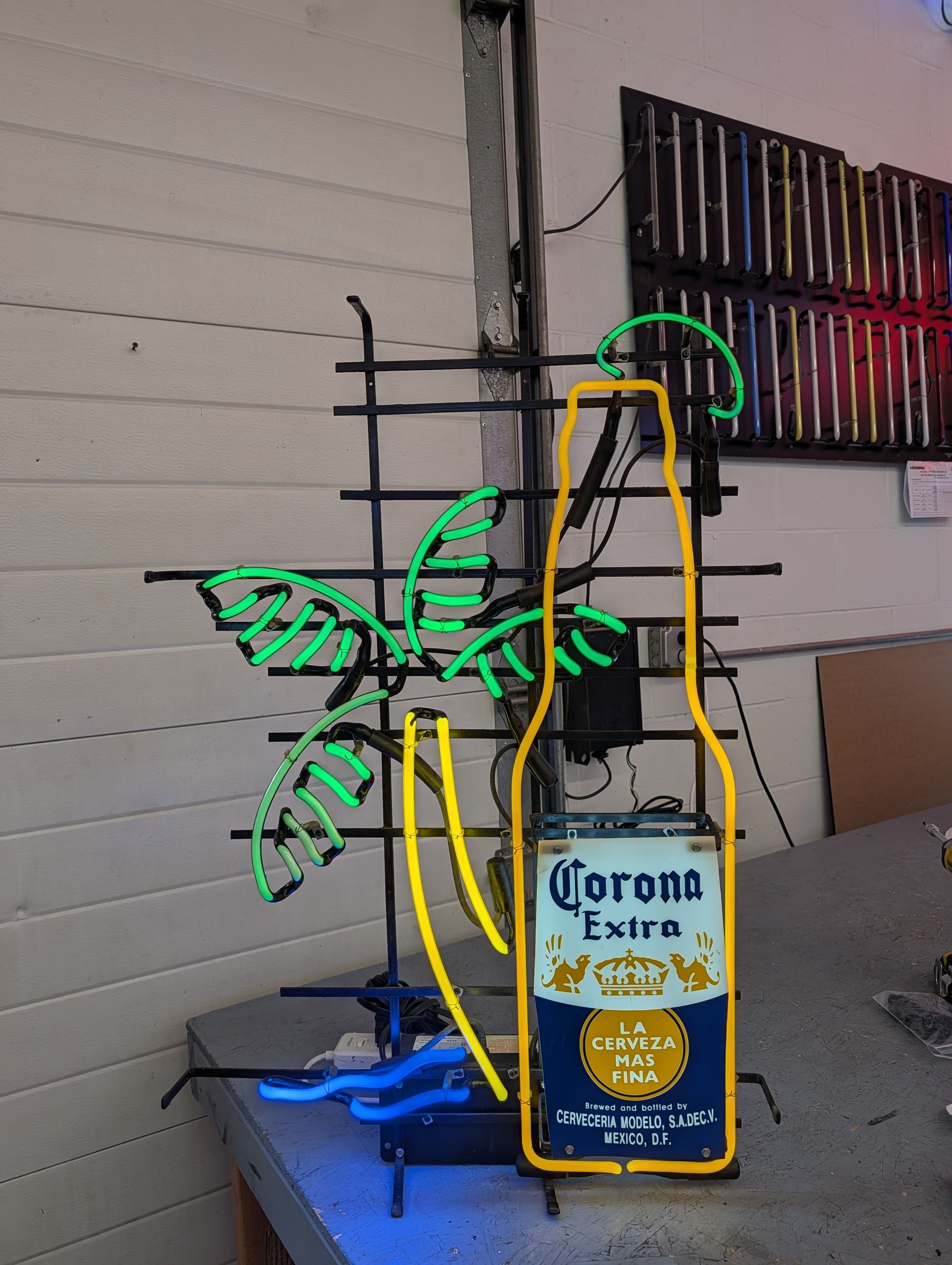 Two Corona beer bottles with a neon green doodle overlay on a patio table by a wall.