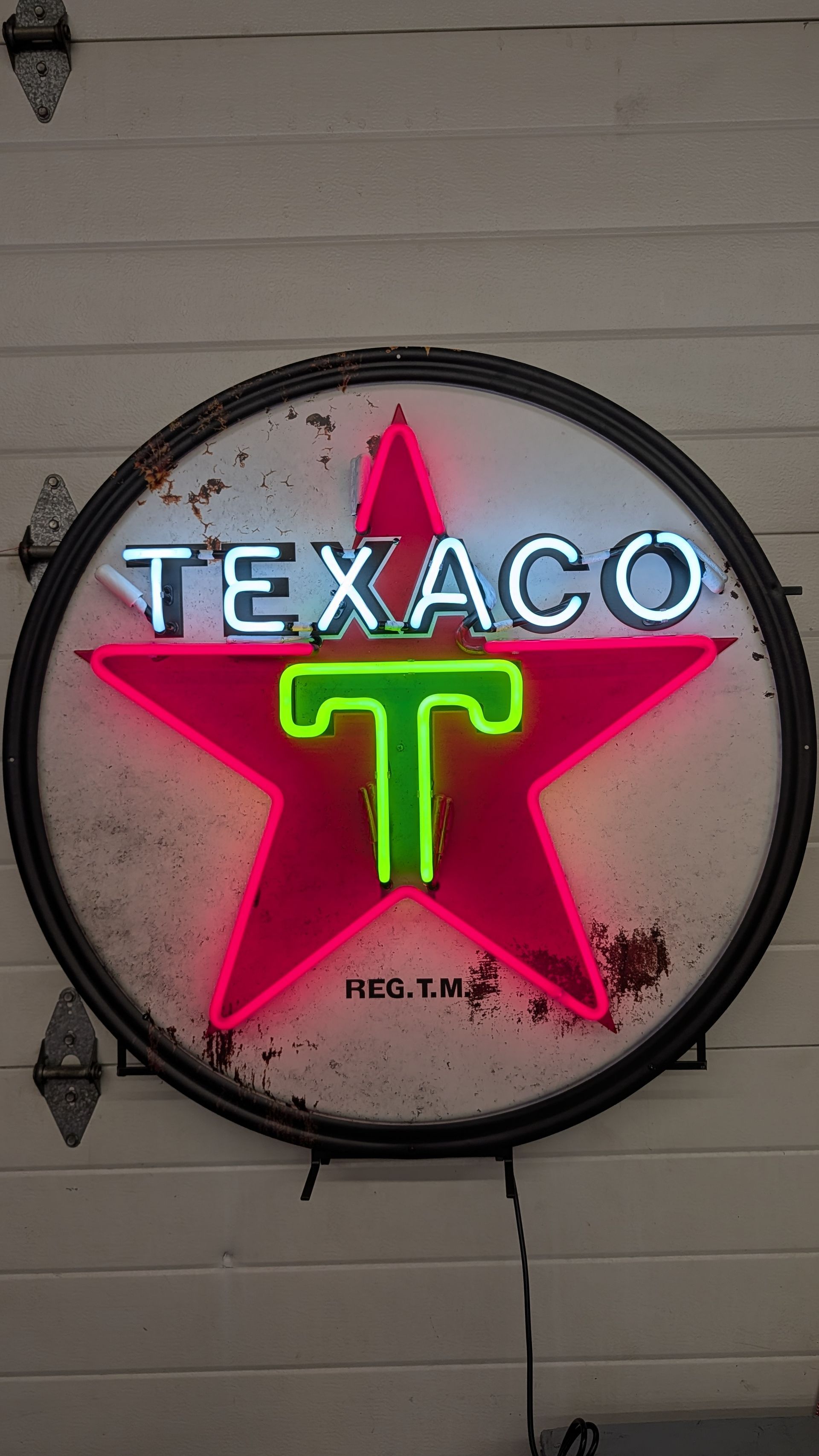Neon Texaco star sign with red star and green T on a round wall plaque