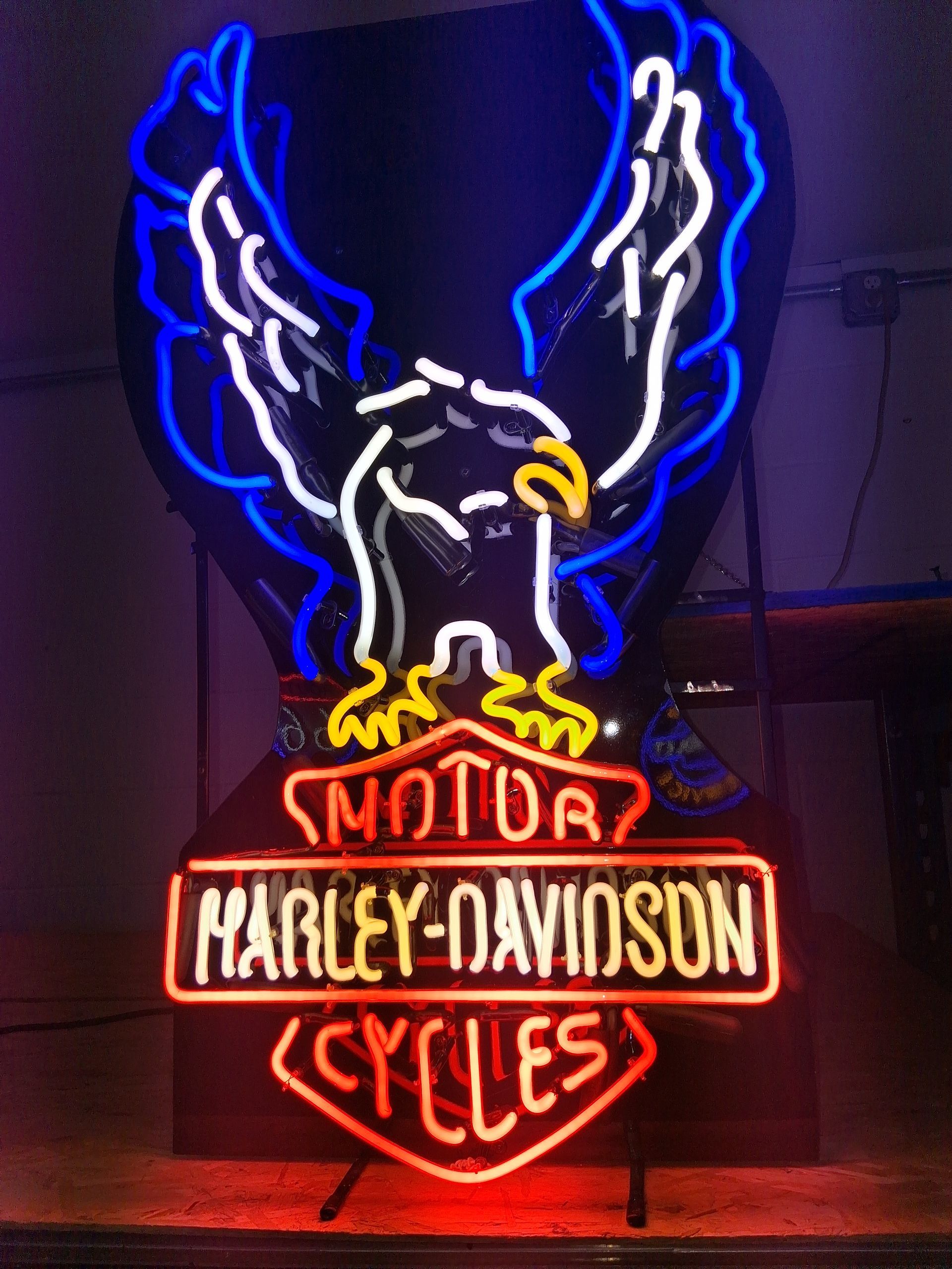 Neon Harley-Davidson sign with an eagle, glowing blue, white, red, and yellow