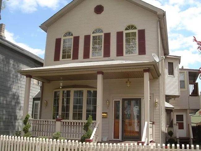 Two-story tan house with maroon shutters and a covered front porch