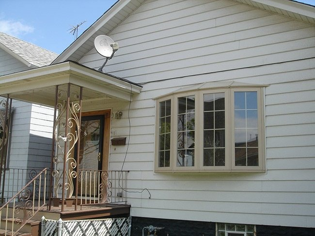 White house exterior with front porch, bay window, and satellite dish