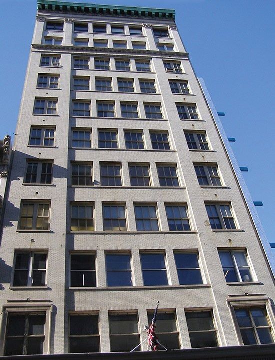 Tall beige building with many windows against a blue sky