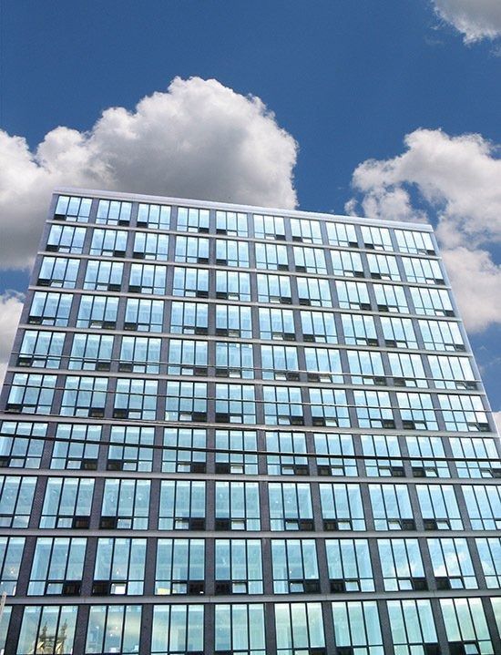 Modern glass office building against a blue sky with white clouds