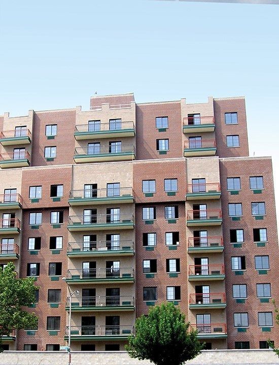 Brick apartment building with balconies and windows against a clear sky