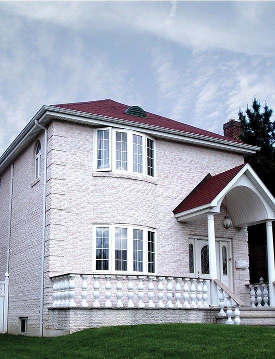 Two-story white brick house with a red roof and arched front porch