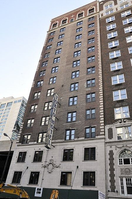Tall brick apartment building with many windows and a white storefront at street level