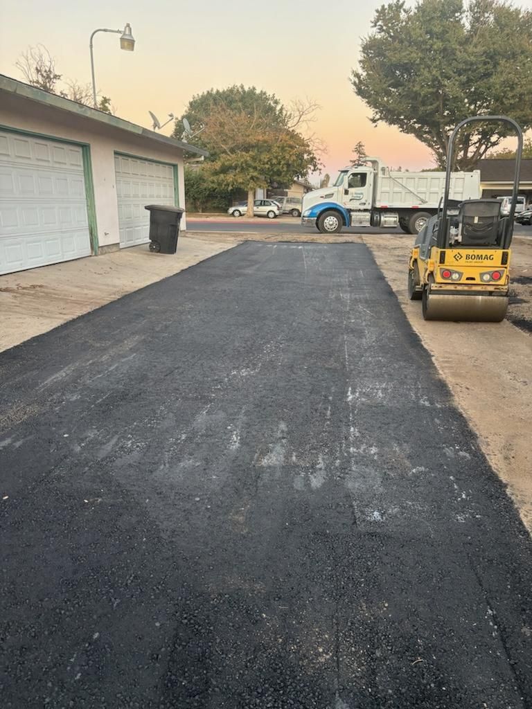 A truck is parked on the side of the road next to a road roller.