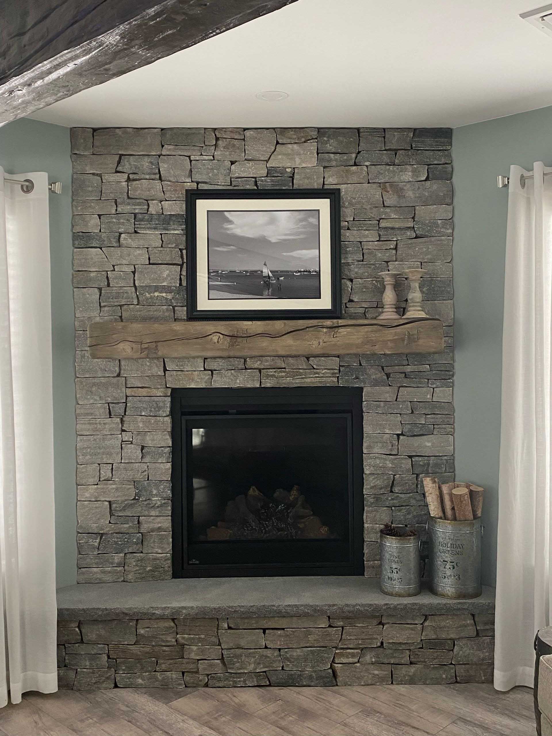 Stone fireplace with black framed picture, wooden mantle, and teal walls.