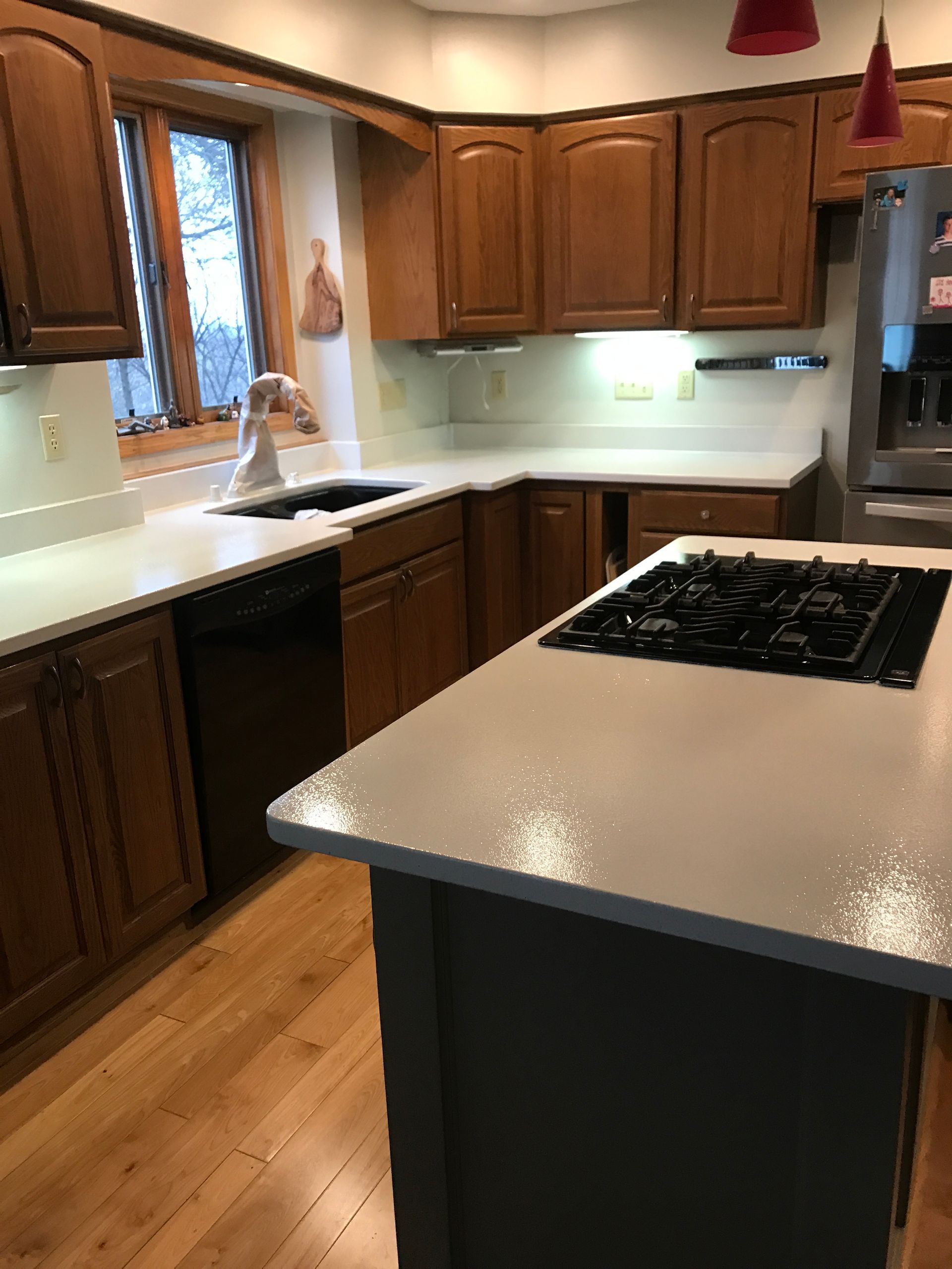 A kitchen with a stove top oven, refrigerator, sink, and dishwasher - after