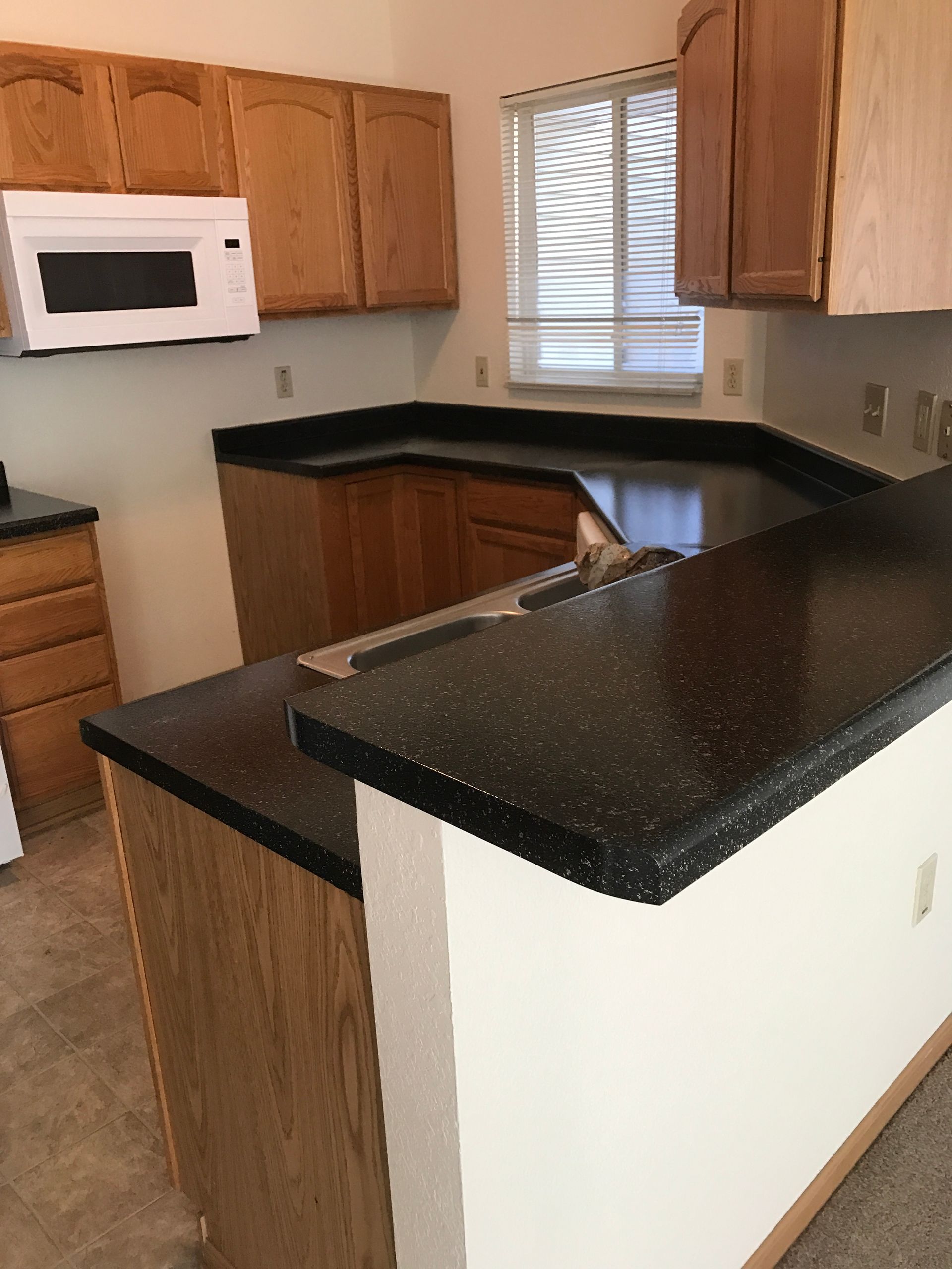 A kitchen with brown cabinets and a white microwave - after