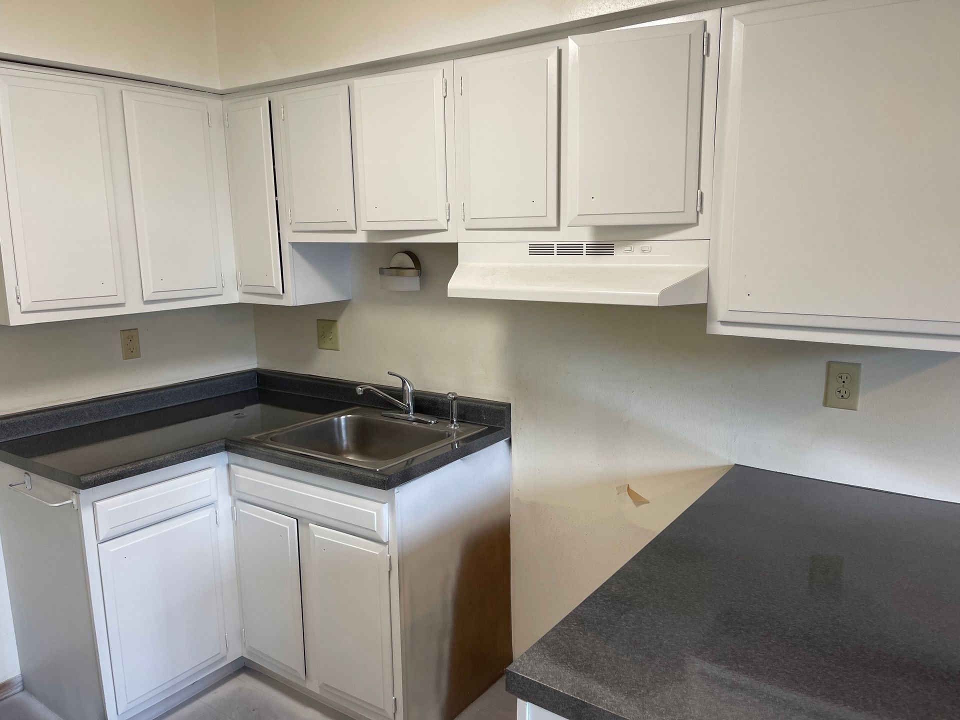 A kitchen with wooden cabinets and a stainless steel sink - after