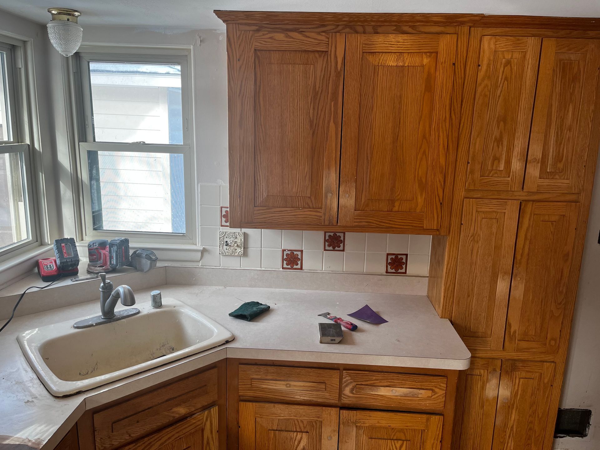 A kitchen with wooden cabinets, a sink, and a window - before