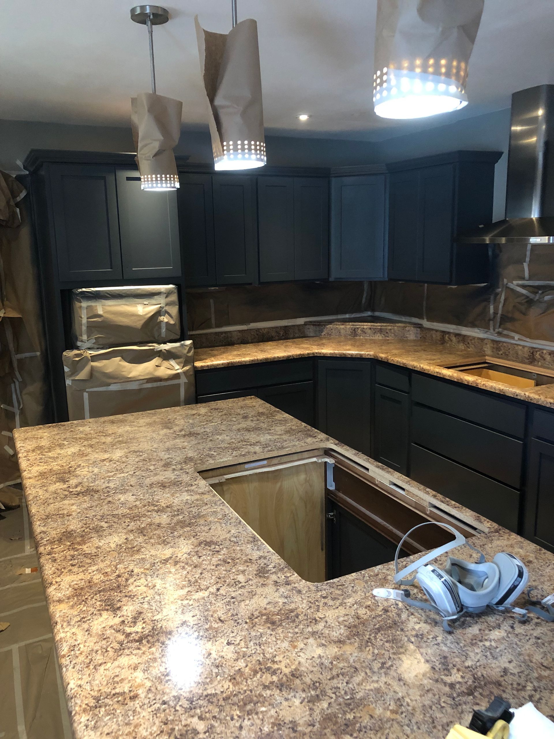 A kitchen with granite countertops and black cabinets is being remodeled - before