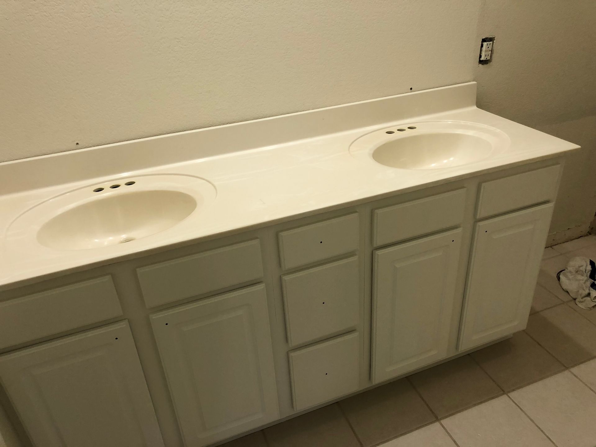 A bathroom with two sinks and white cabinets - before