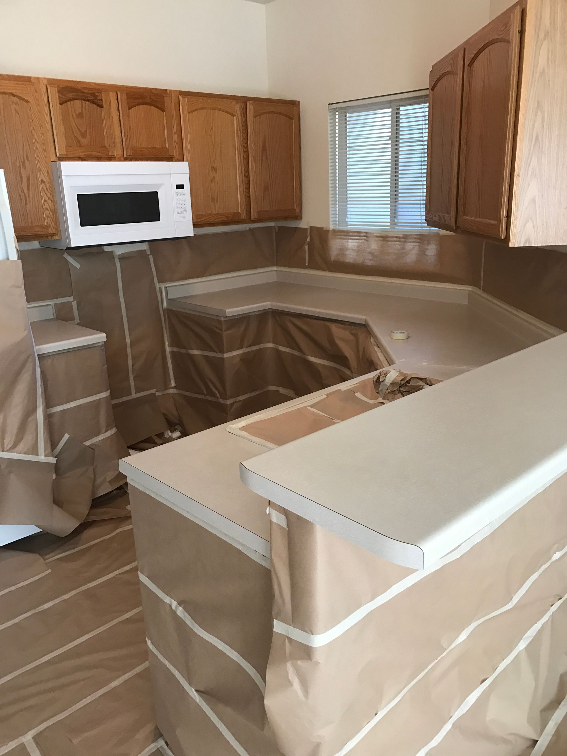 A kitchen with brown cabinets and a white microwave - before