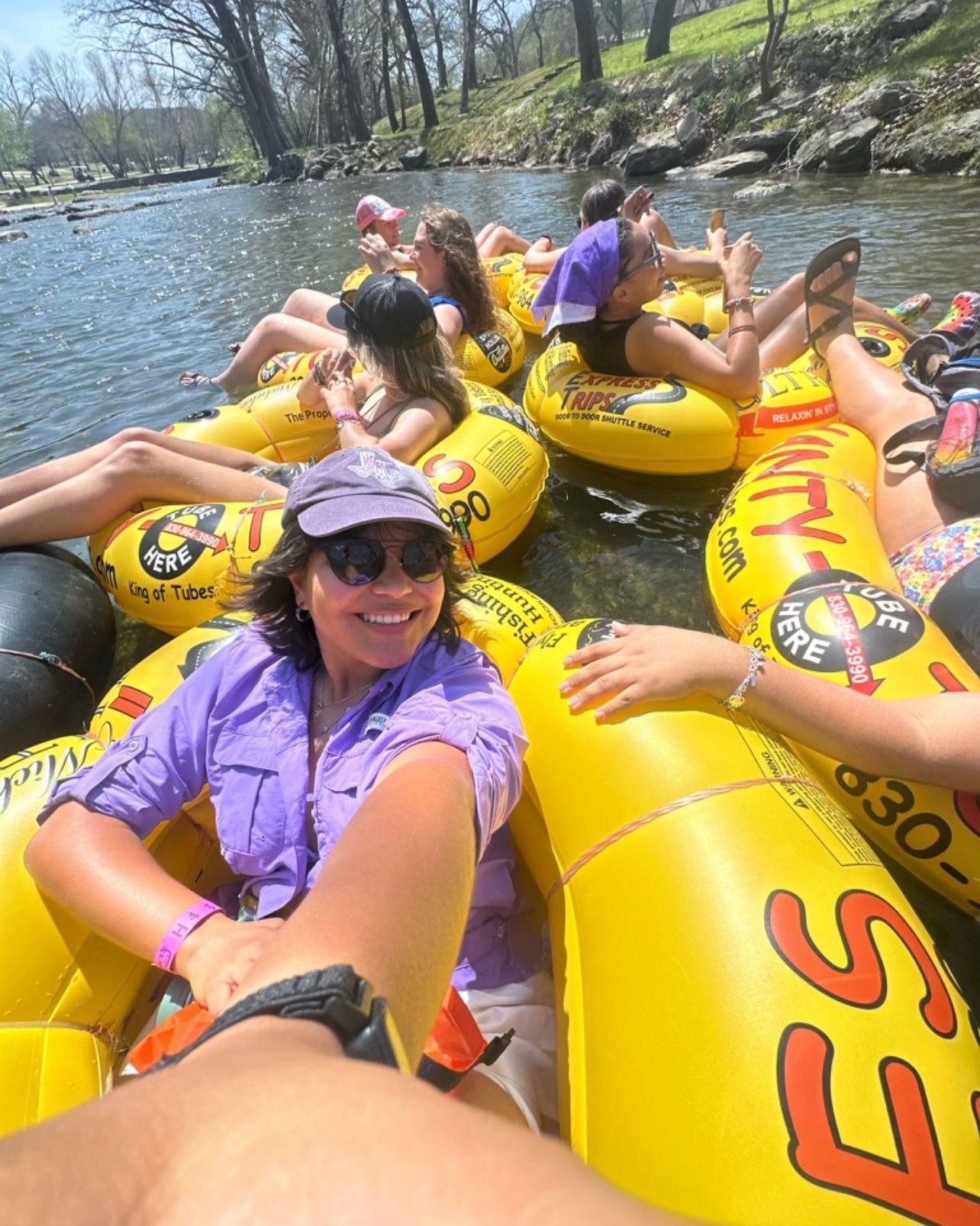 A group of people are floating down a river in yellow tubes.