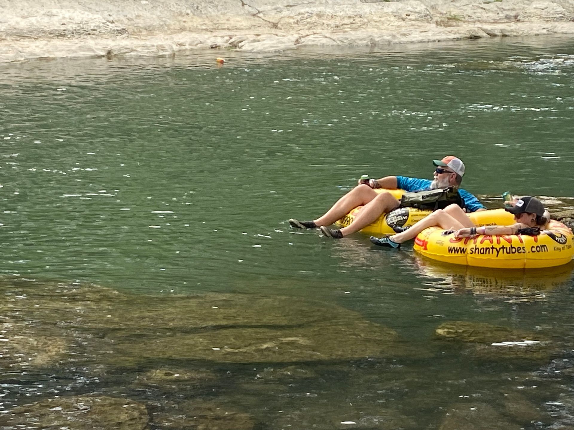 A man and a woman are floating on tubes in a river.