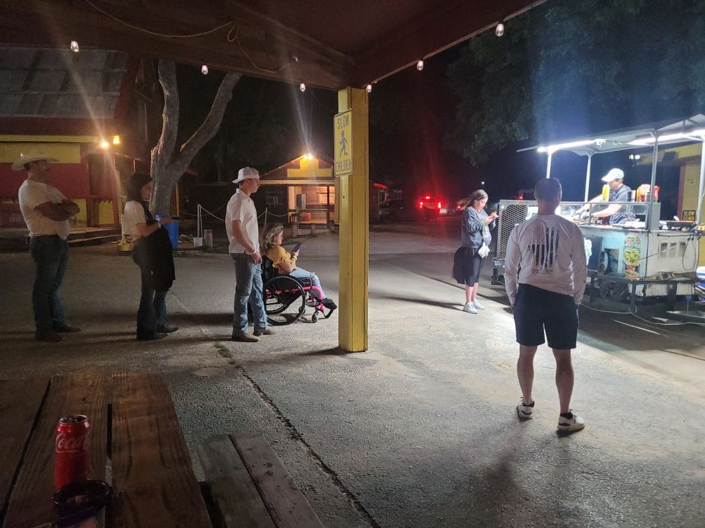 A group of people are standing in front of a food truck at night.