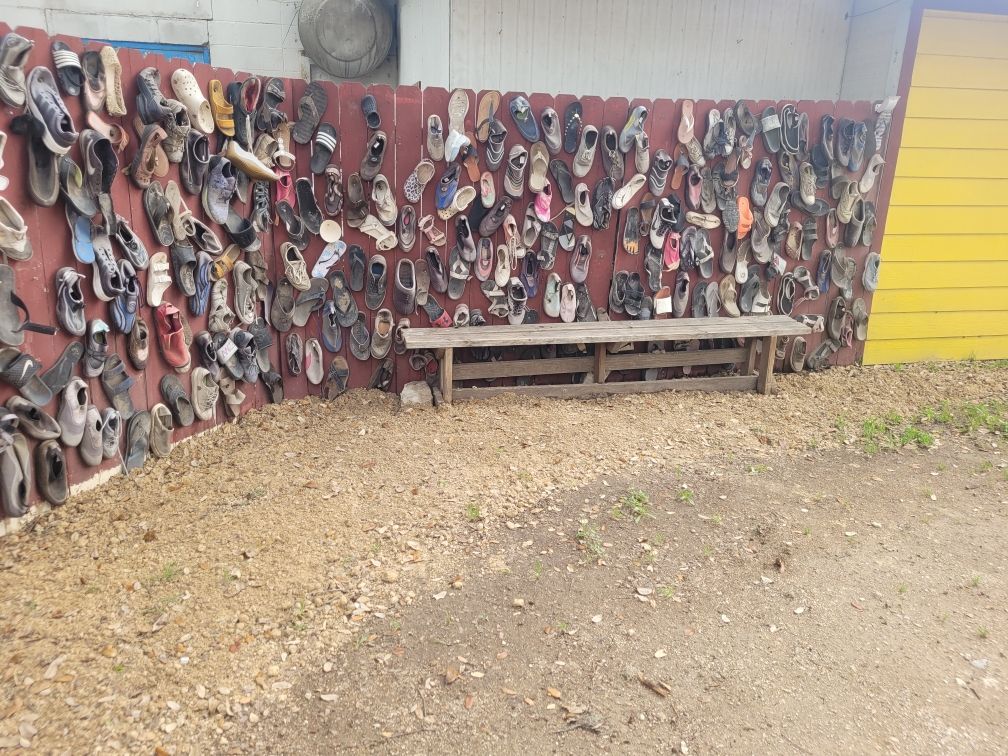 A fence with a lot of shoes hanging on it