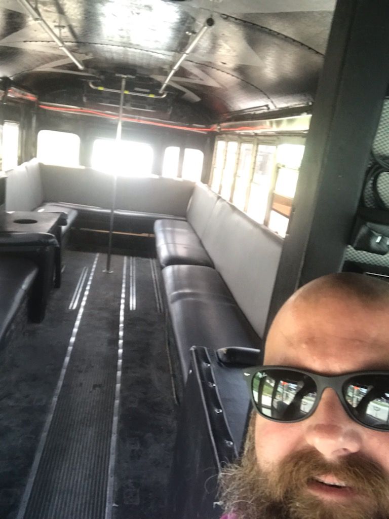 A man with a beard is taking a selfie in the back of a bus.