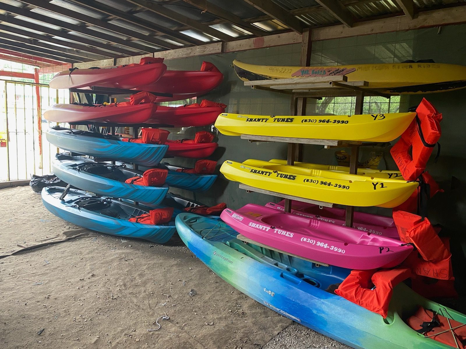 A bunch of kayaks are lined up on a rack.