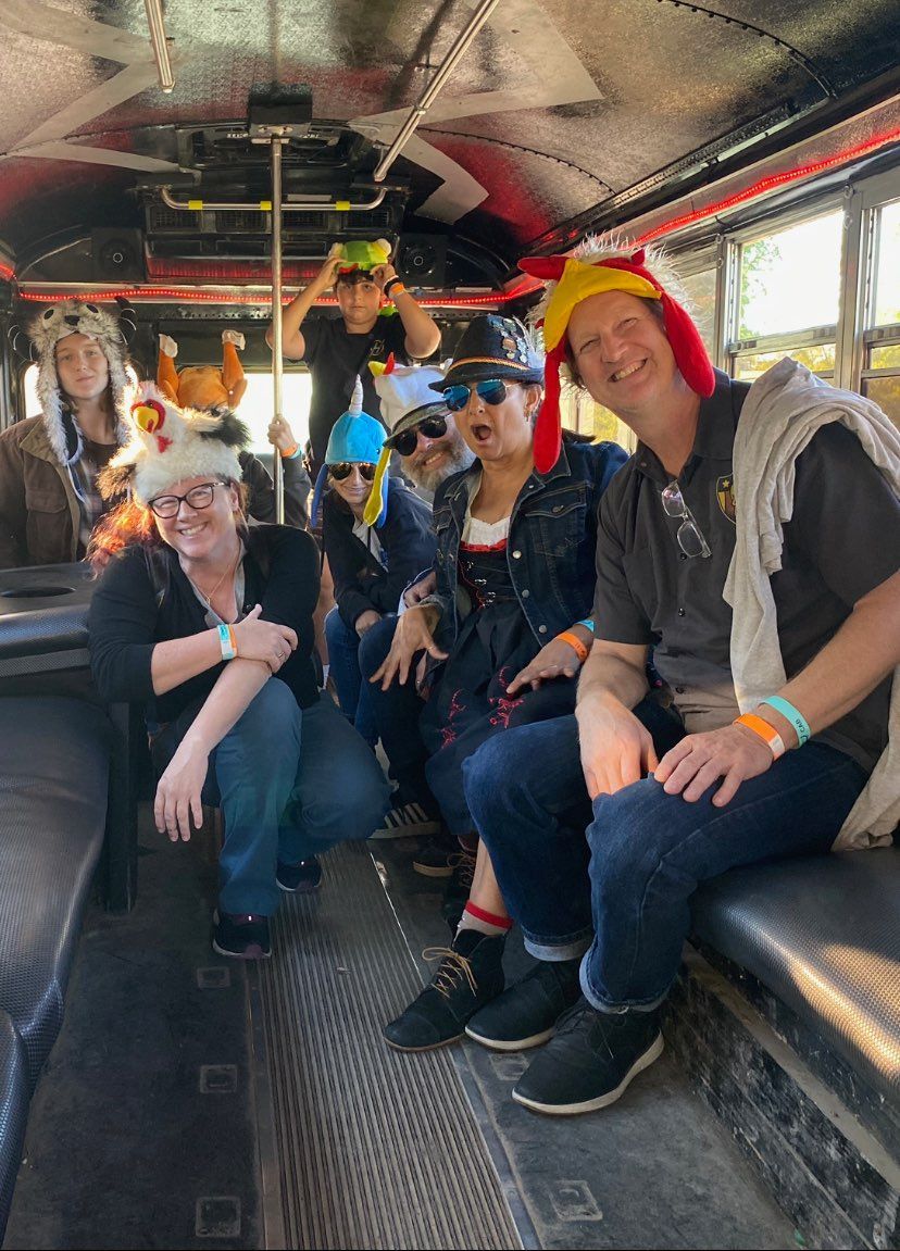 A group of people are sitting on a bus wearing chicken hats.