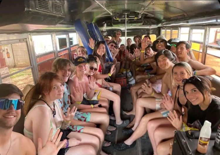 A group of people are sitting on a bus waving at the camera.