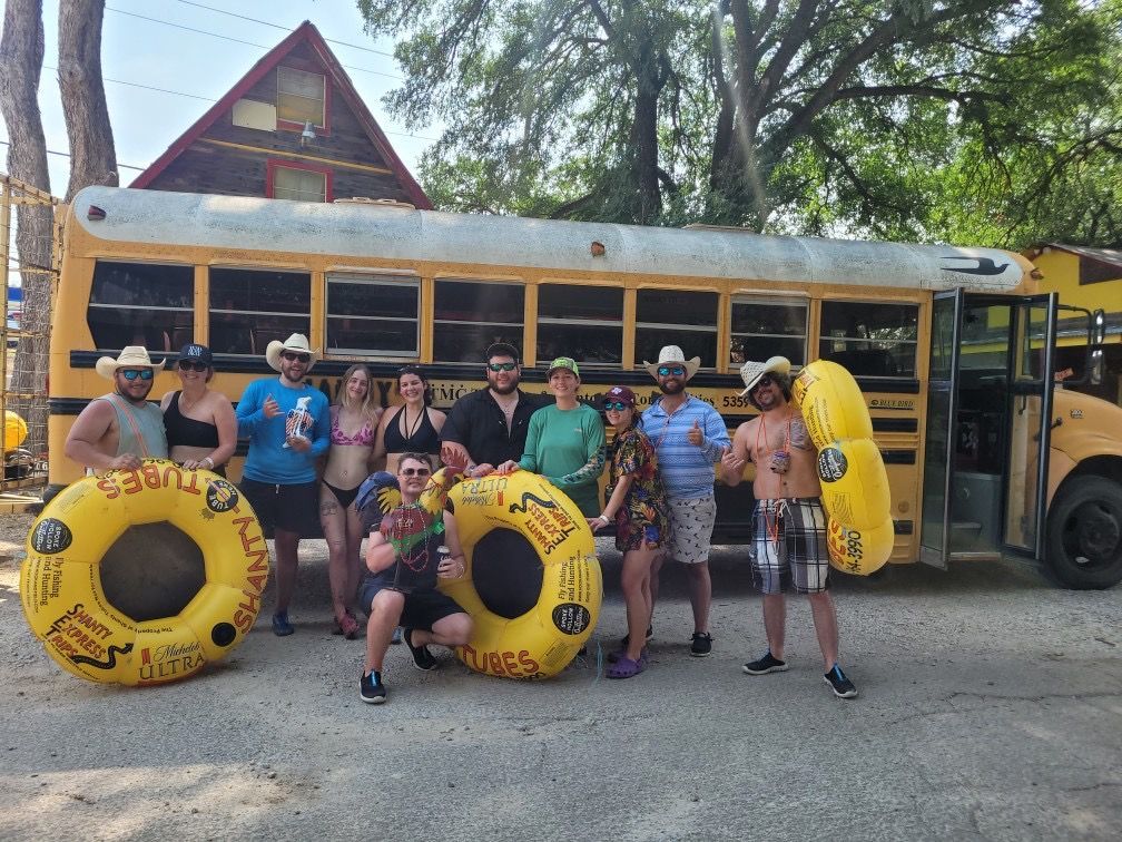 A group of people are posing for a picture in front of a yellow school bus.