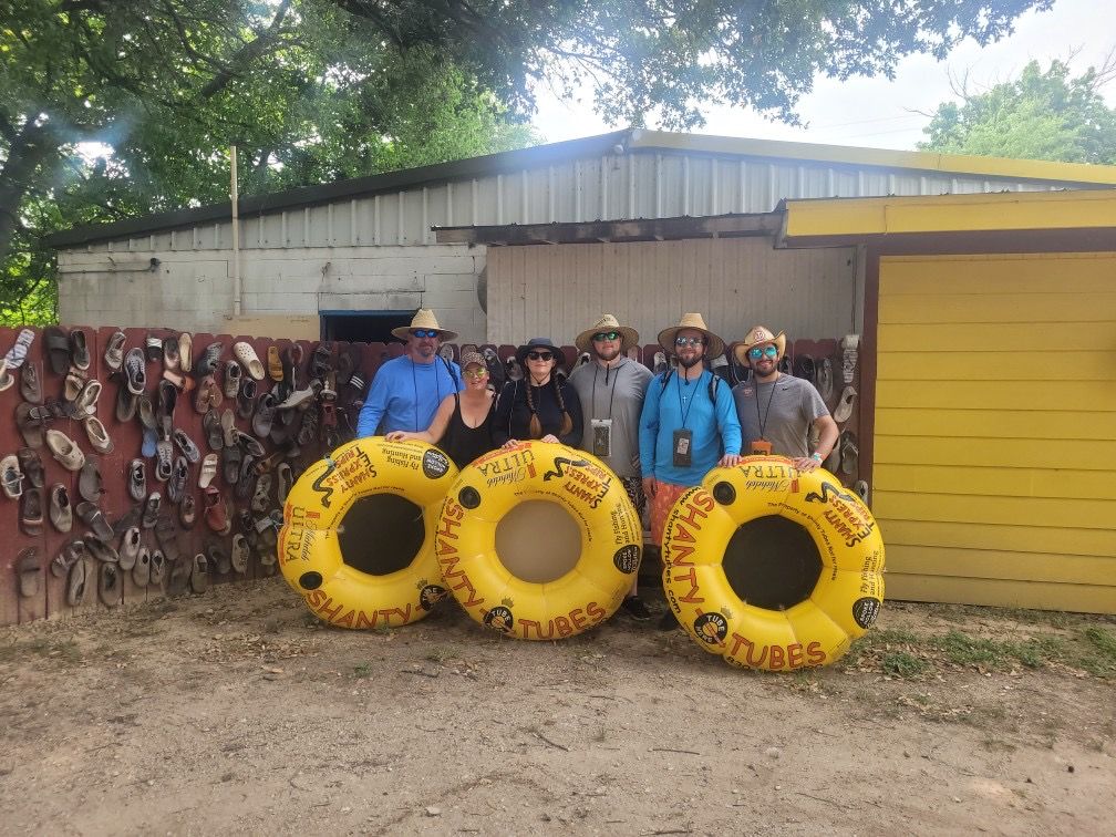 A group of people are posing for a picture with three yellow tubes in front of a building.