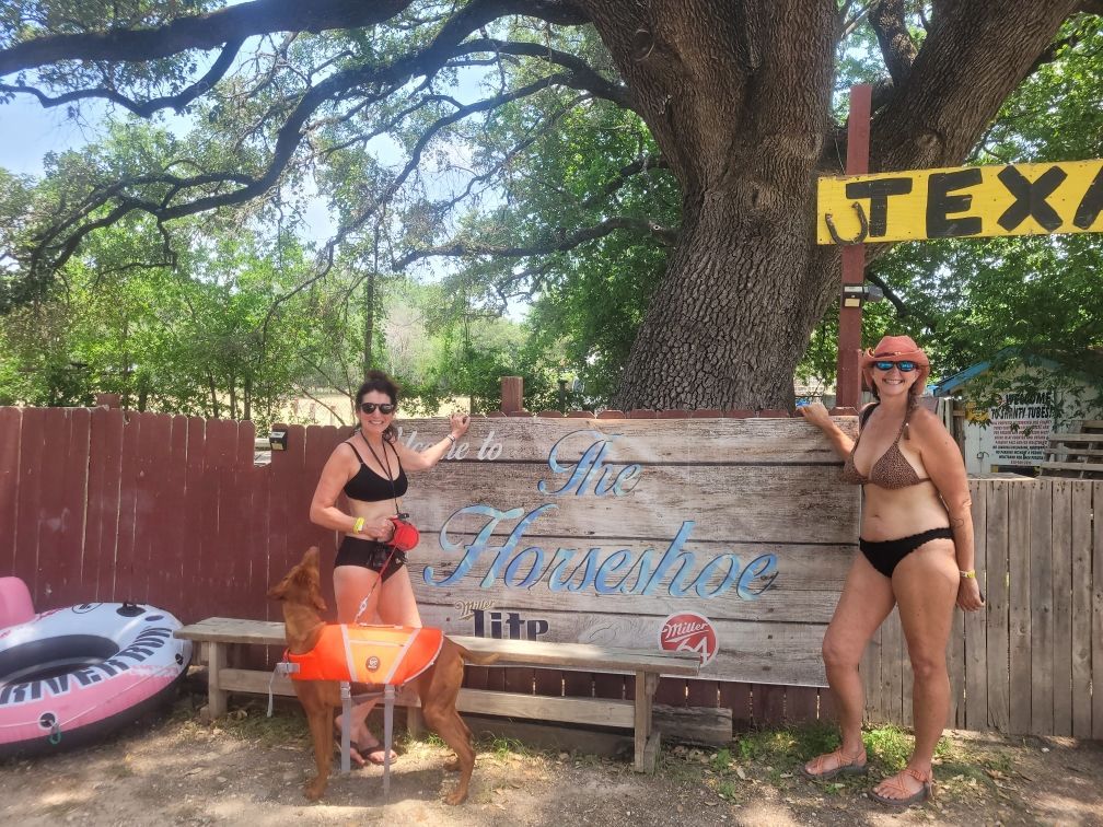 Two women in bikinis are standing in front of a sign that says tex