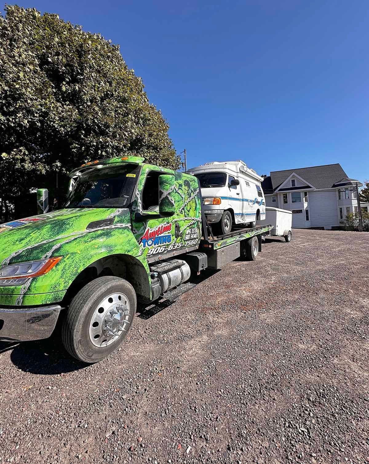 Tow truck with a small camper on its flatbed
