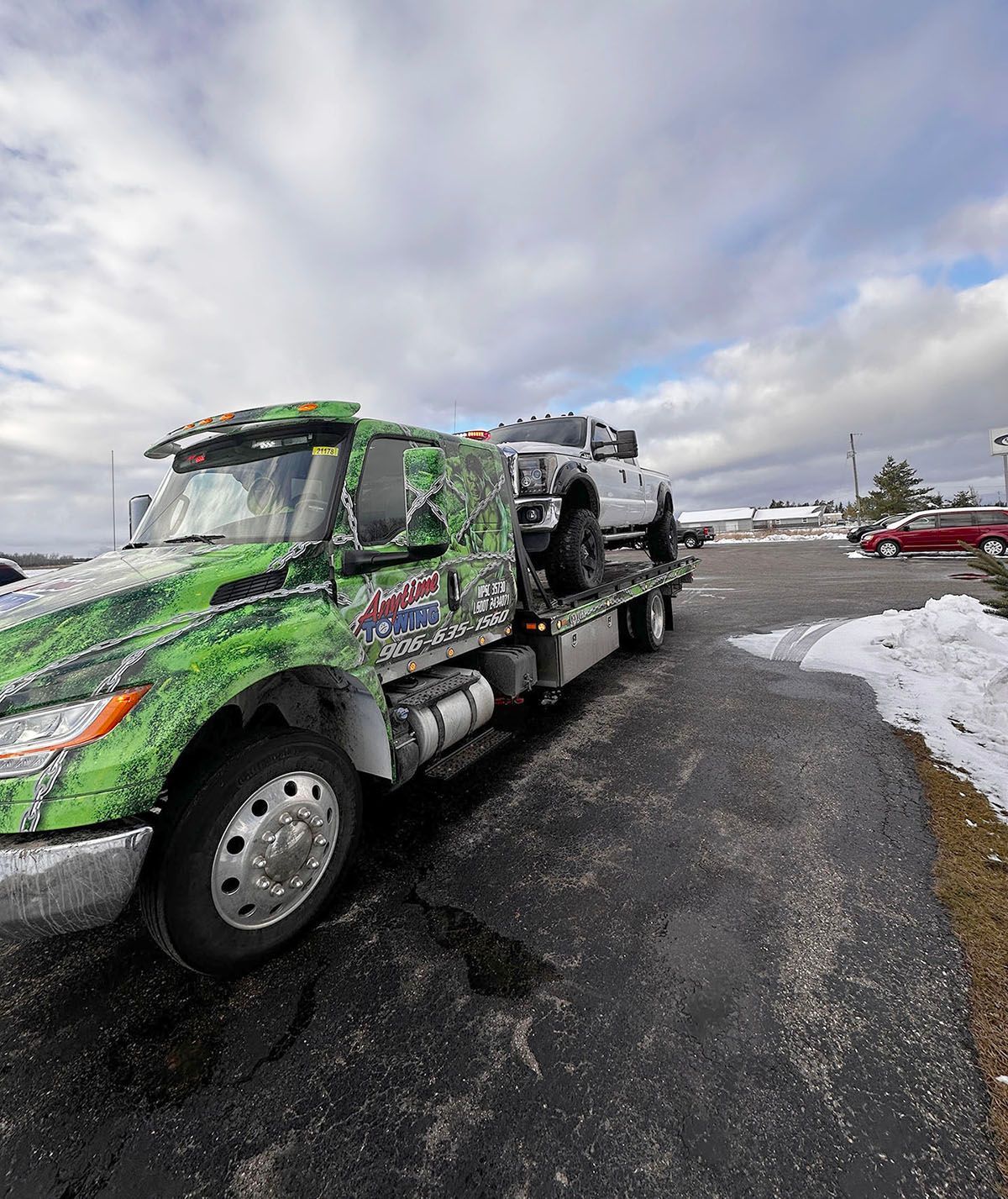 Tow truck with a white pickup truck on its bed