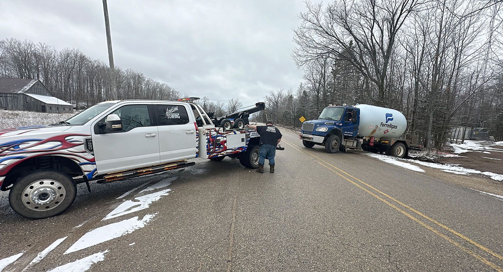 Tow truck hooking up to a tanker truck