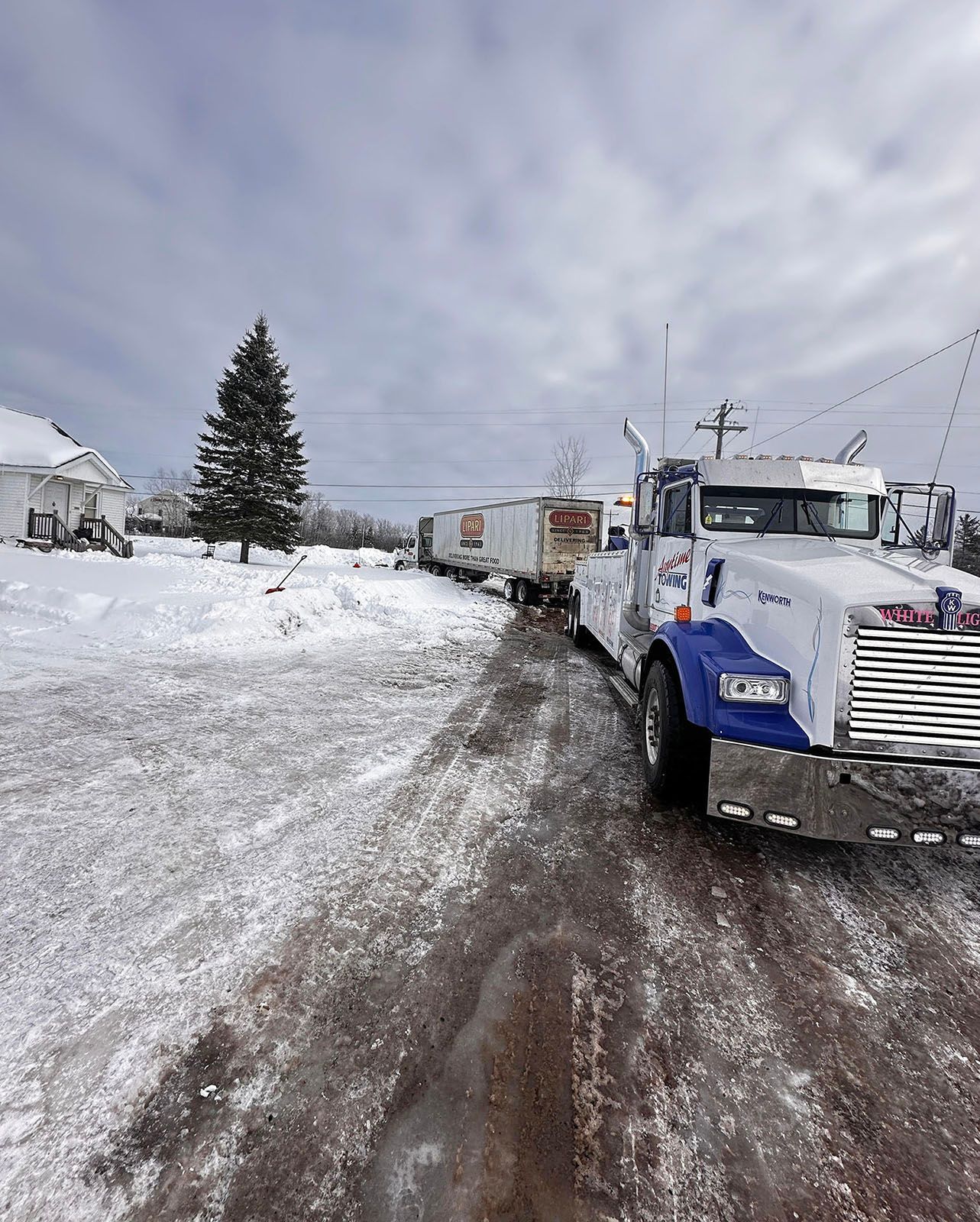 Tow truck towing cargo trailers on a snow-covered road