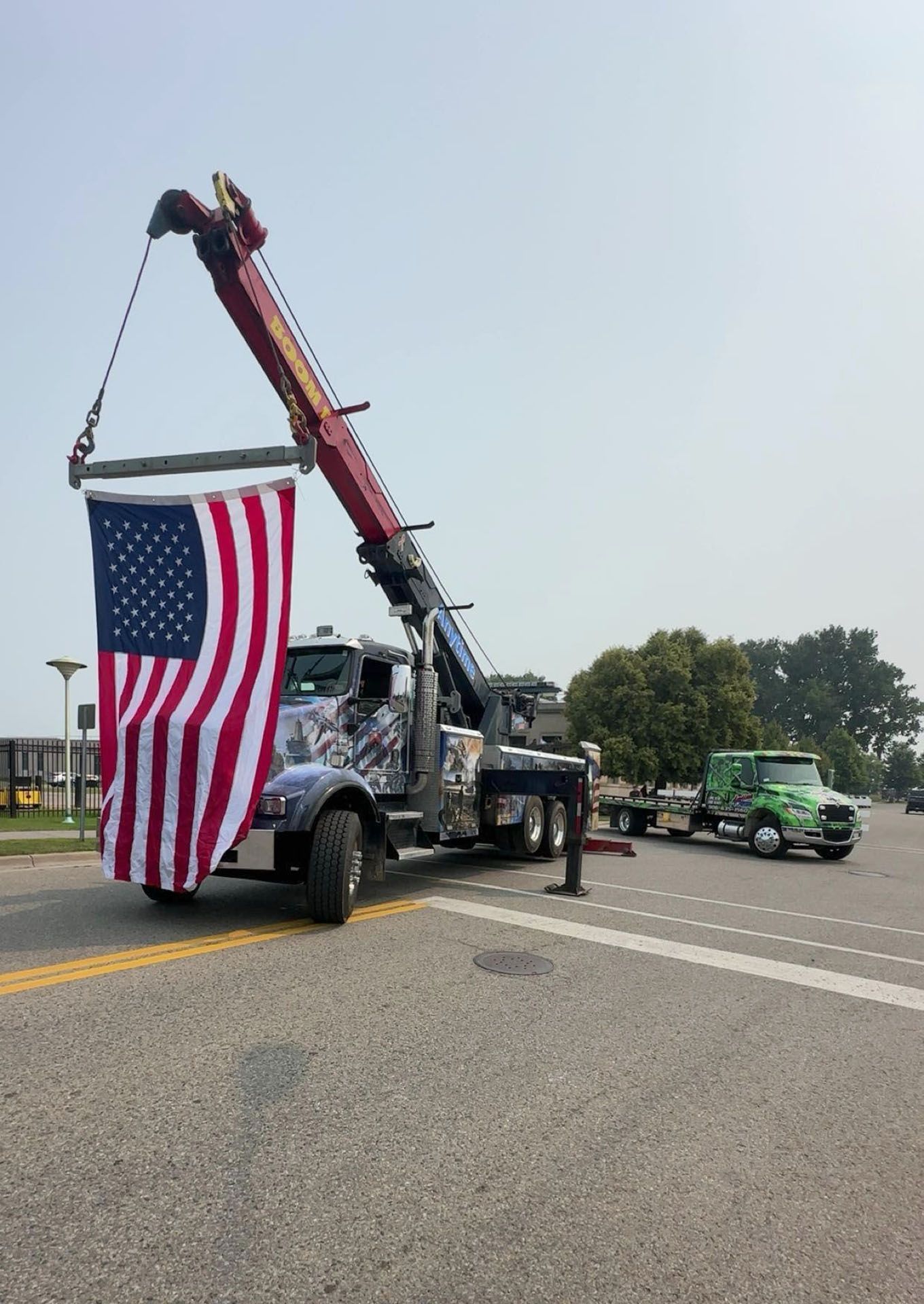 Tow truck with raised boom holding American flag