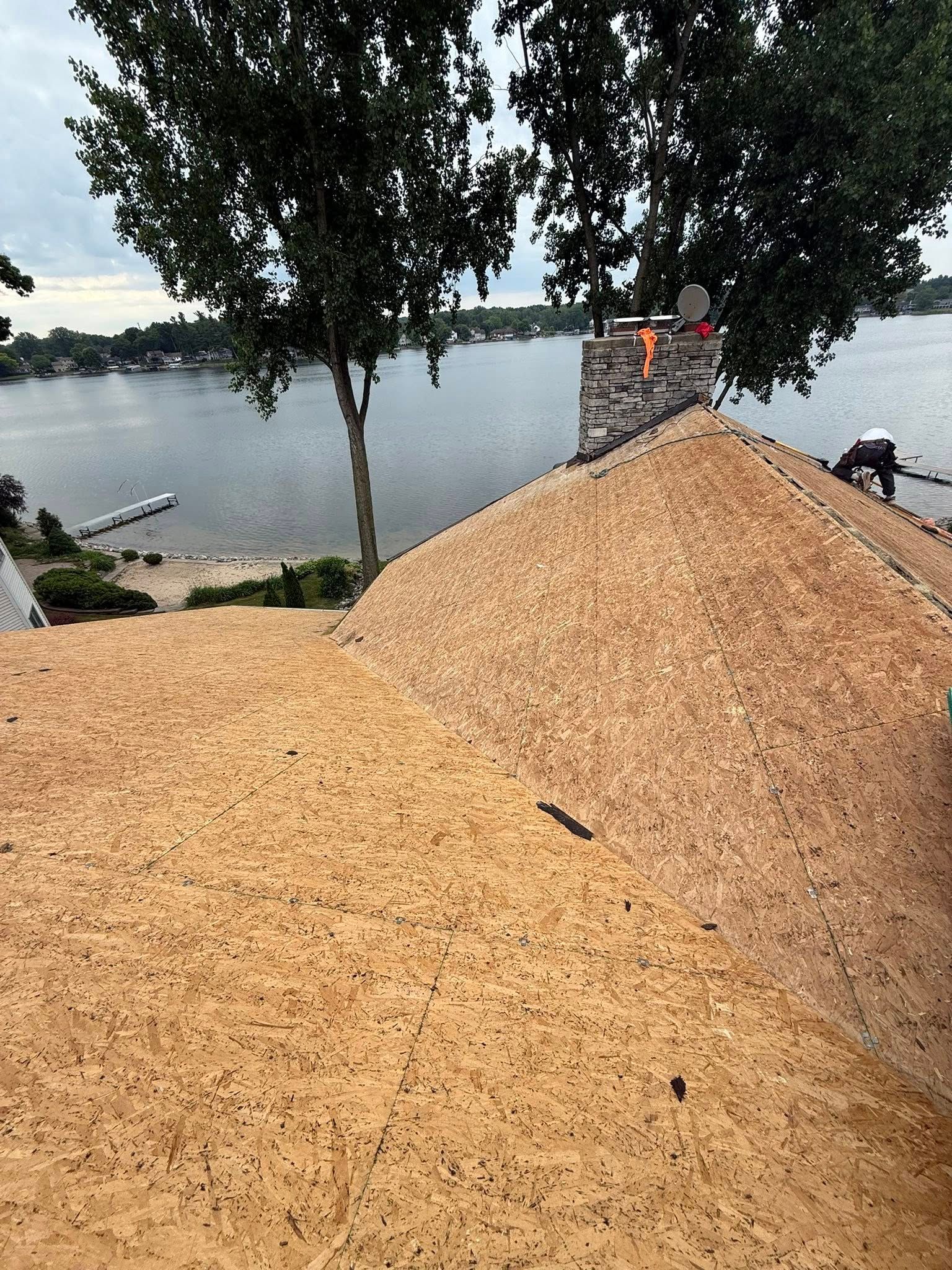 A man is working on a roof overlooking a lake.