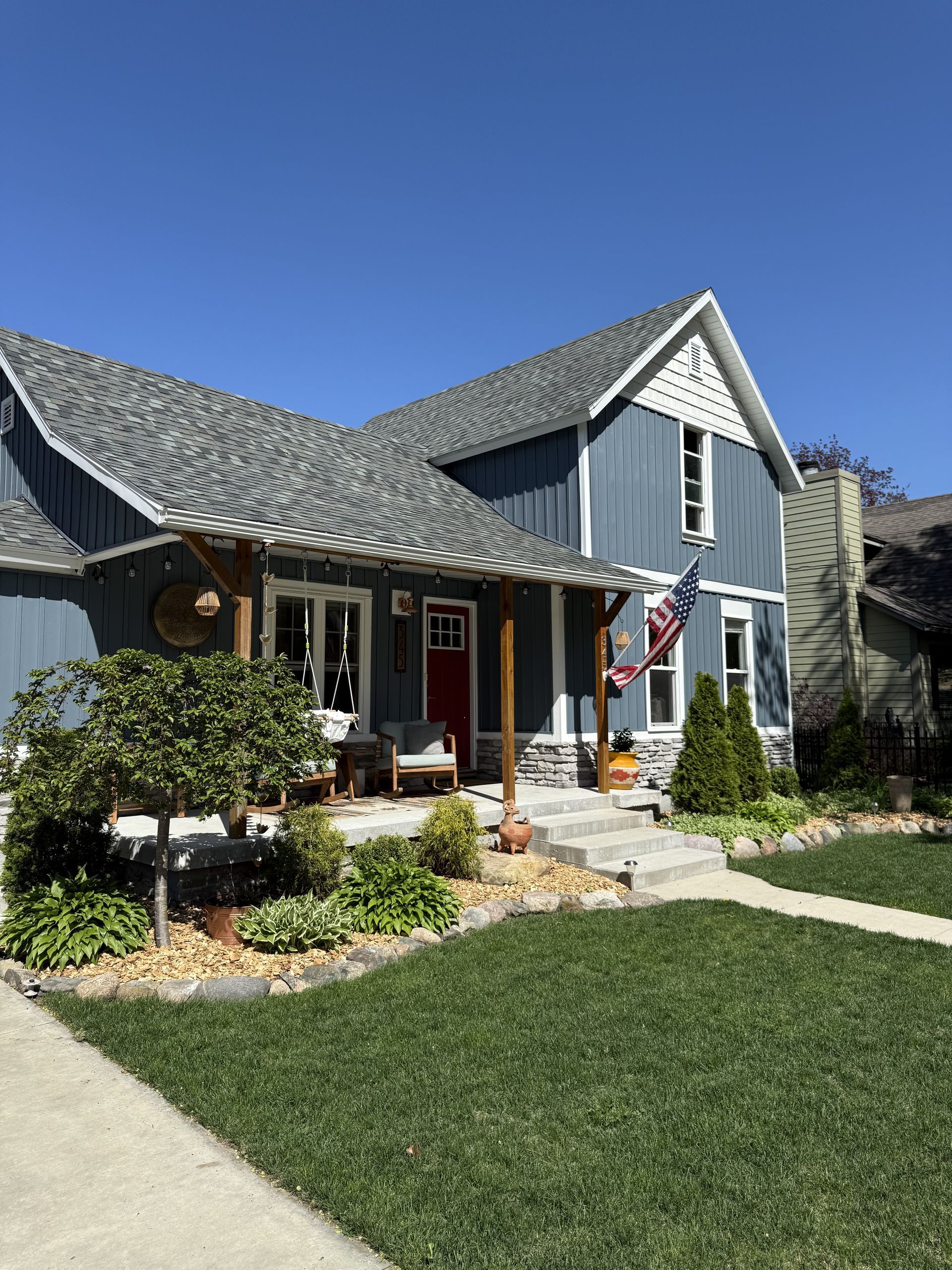 A blue house with a red door and a pergola on the front porch.