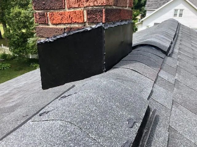 A brick chimney is sitting on top of a roof.