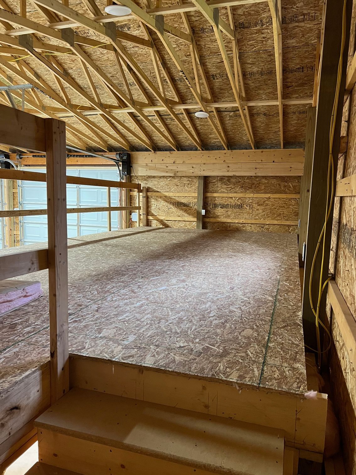 A wooden barn with stairs leading up to it and a wooden floor.
