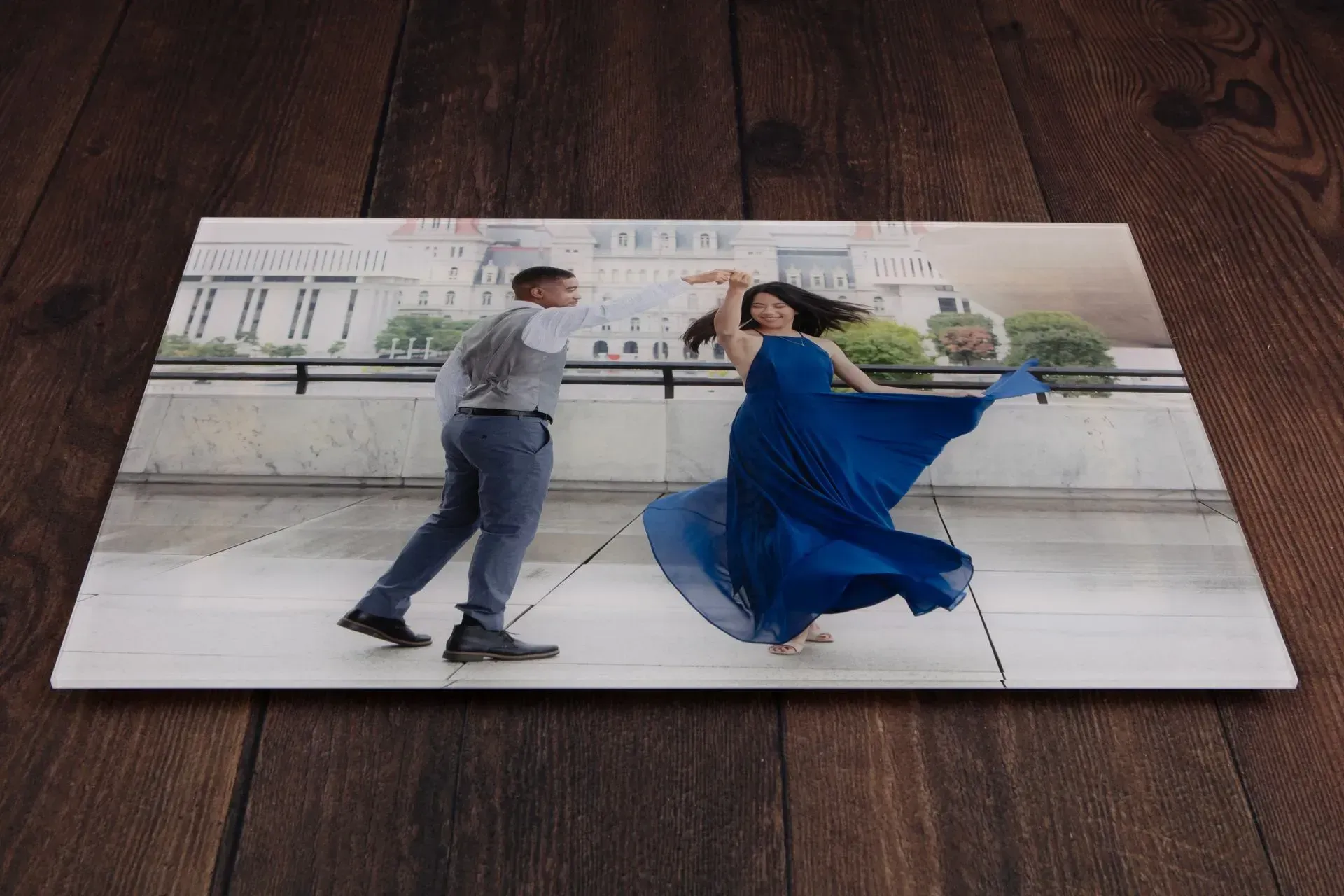 Couple dancing in a blue dress and suit on a city balcony.