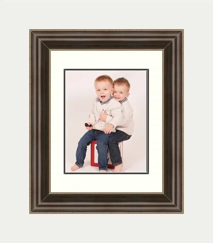 Two young children, seated, smiling. Posed within a framed matting.