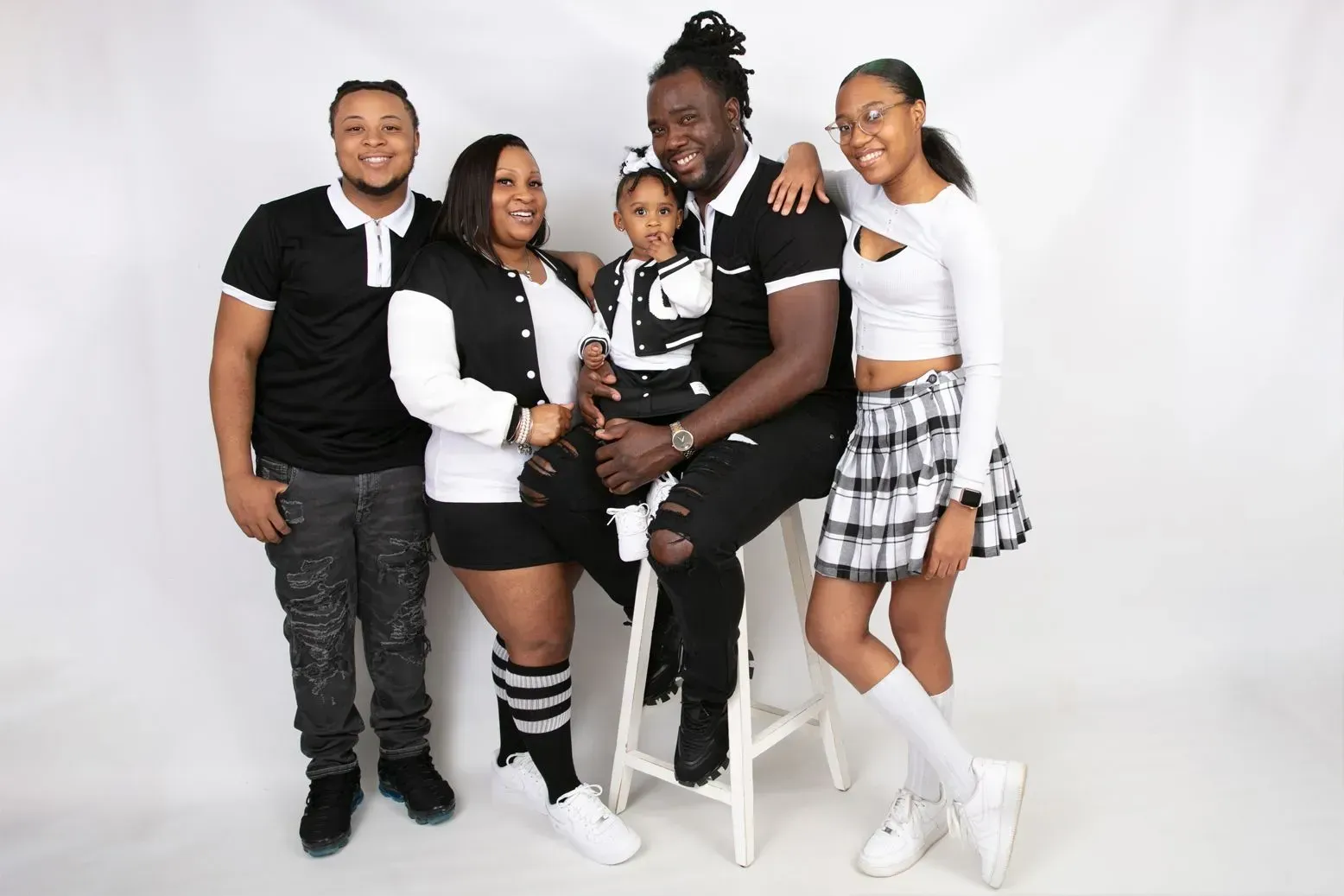 Family of five poses in front of white backdrop, wearing black and white outfits.