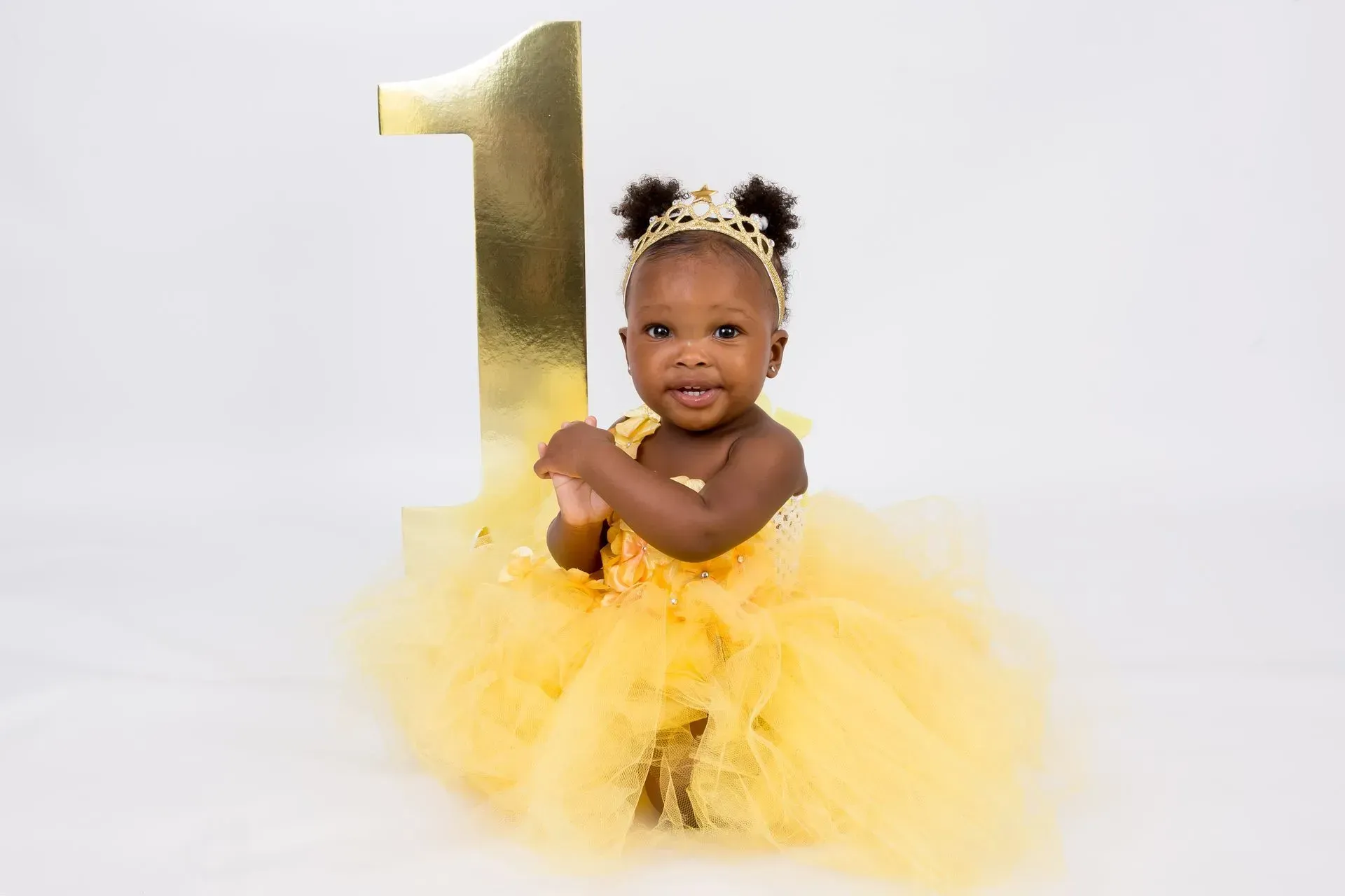 Young child in yellow tutu and crown holds a gold