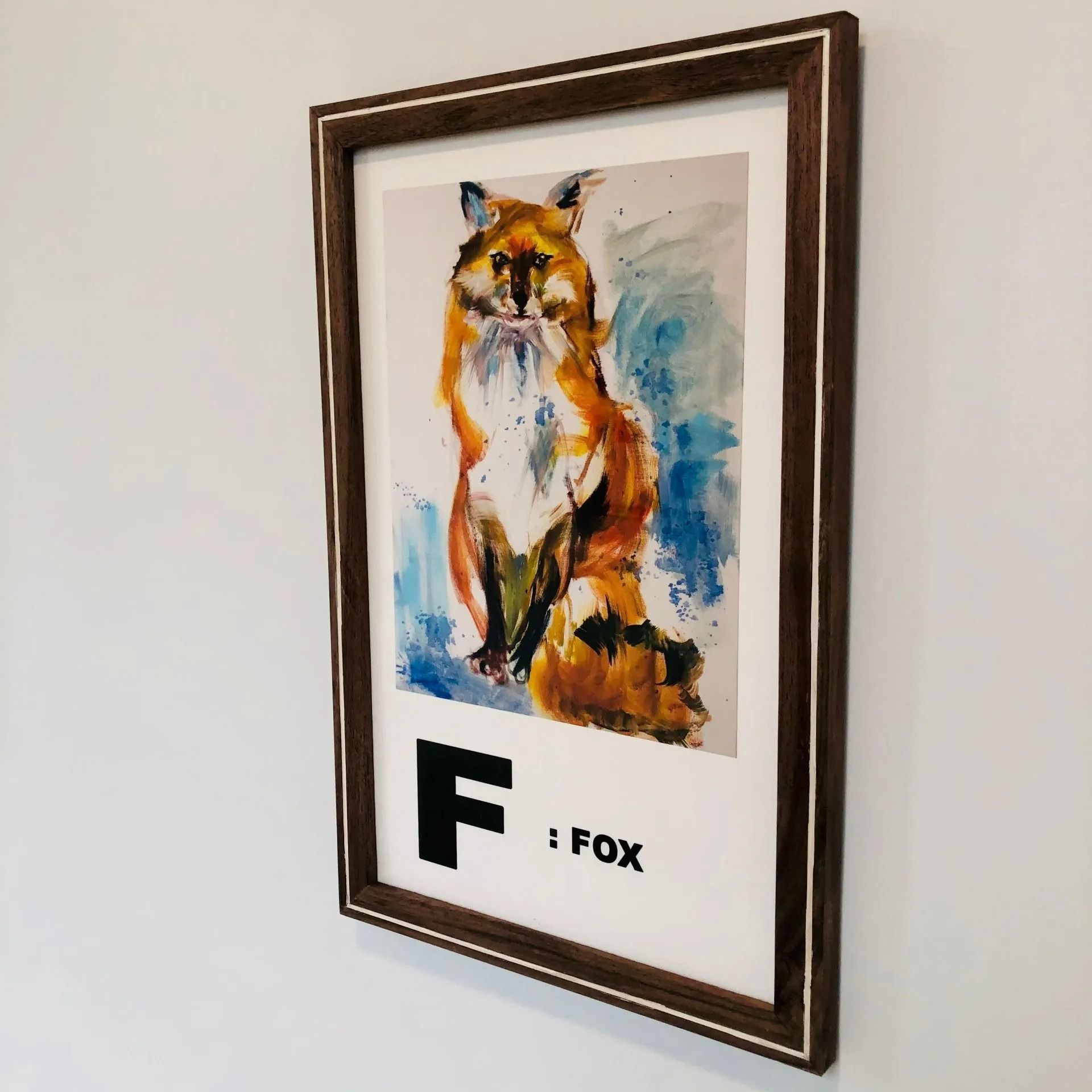Framed fox poster with watercolor-style orange, blue, and white art and the label “F : FOX”