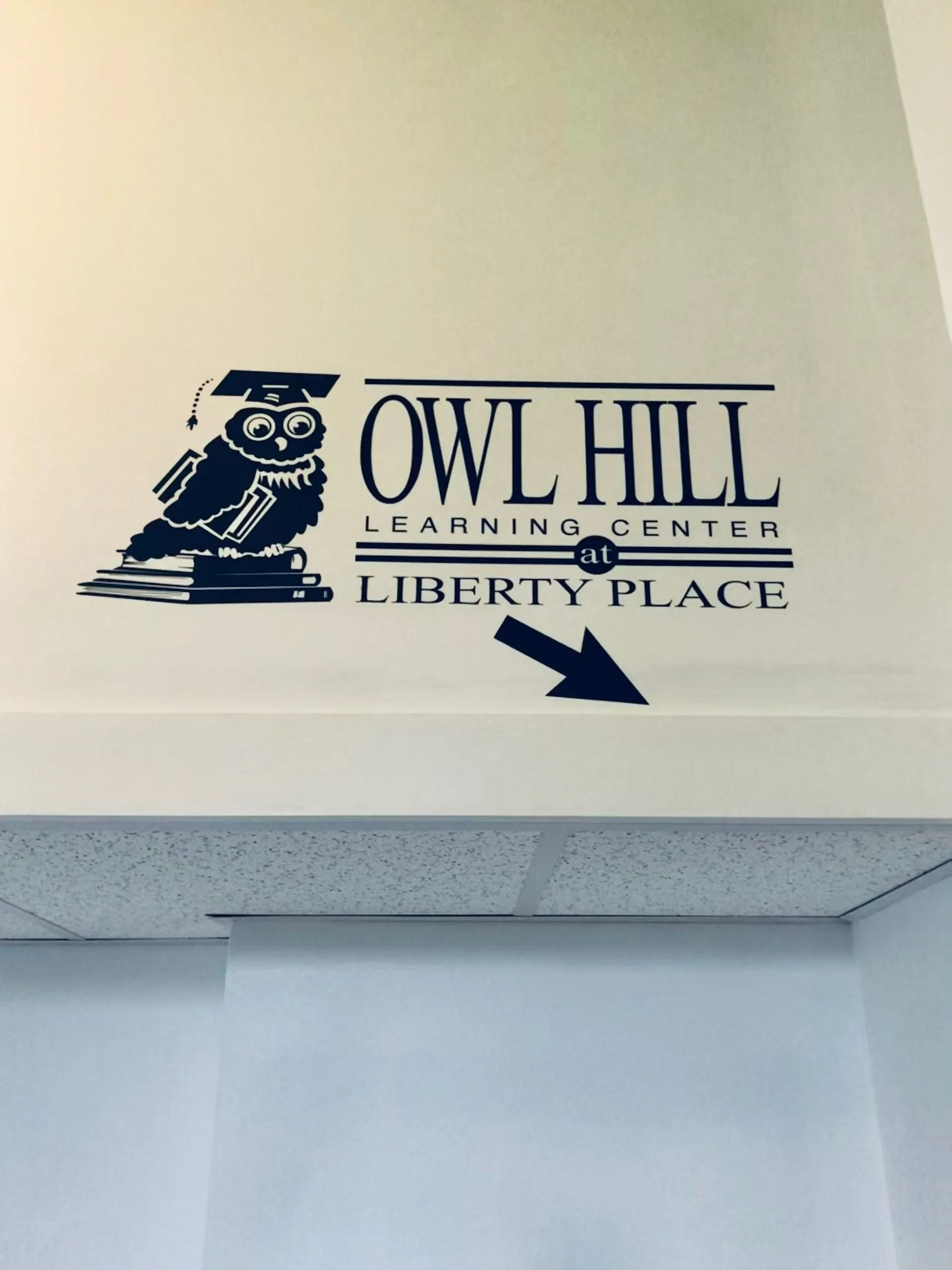 Owl Hill Learning Center Liberty Place logo in navy on a wall