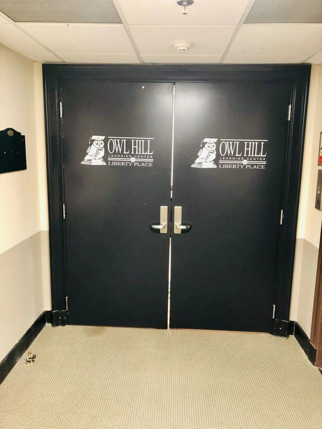 Black double doors with white logos in a hallway, viewed head-on.