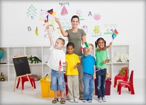Children painting in a bright classroom, with a smiling teacher at the whiteboard
