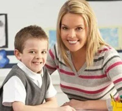 Smiling child and woman sitting at a table in a bright classroom or tutoring setting