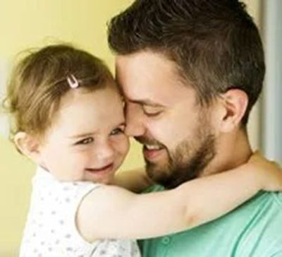 Smiling adult and child hugging closely indoors