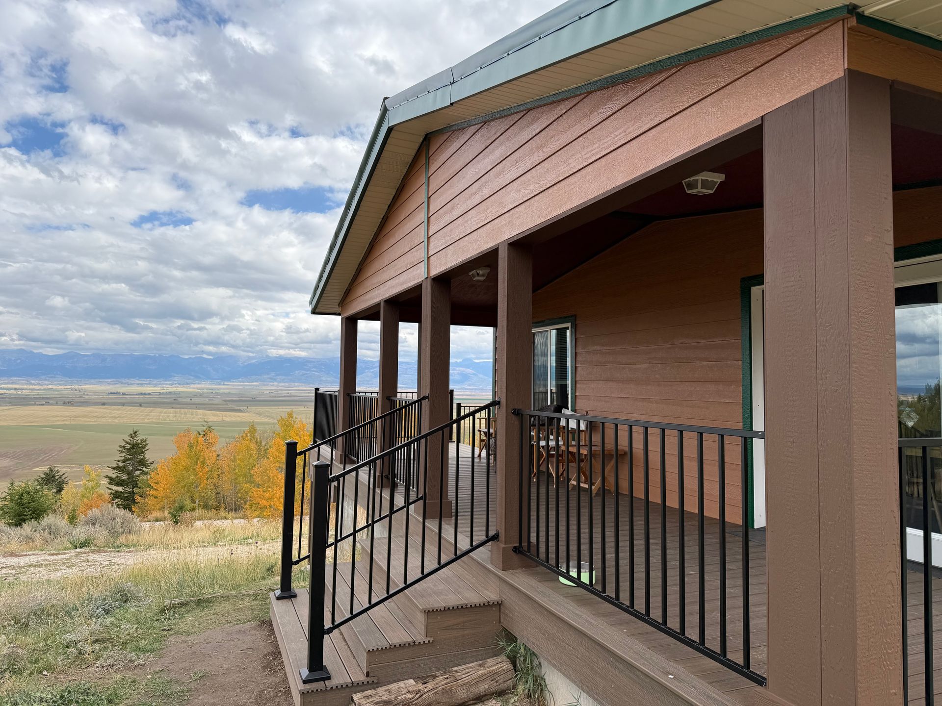 Porch with black railings overlooking a cloudy valley landscape